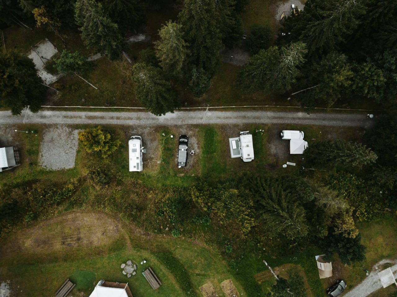 Aerial view of RV sites along a gravel lane among evergreens